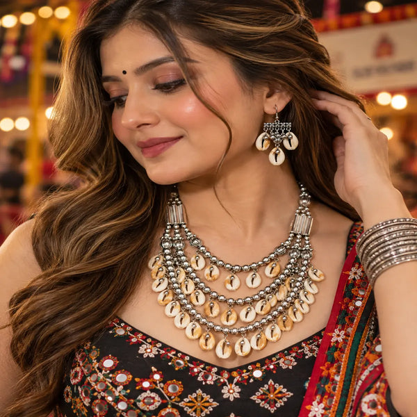 Antique two-tone cowrie shell Navratri necklace set with layered silver-tone beads and matching earrings for women.