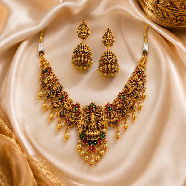 Antique Lakshmi temple jewelry necklace set with traditional jhumka earrings, ruby and emerald stones, and pearl danglings in South Indian bridal style