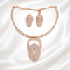 Rose gold necklace set with layered oval geometric pendant and matching earrings, accented with diamond-inspired detailing, displayed on a satin background showcasing modern luxury jewellery design.