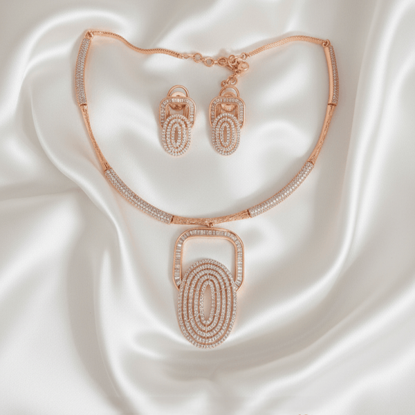 Rose gold necklace set with layered oval geometric pendant and matching earrings, accented with diamond-inspired detailing, displayed on a satin background showcasing modern luxury jewellery design.