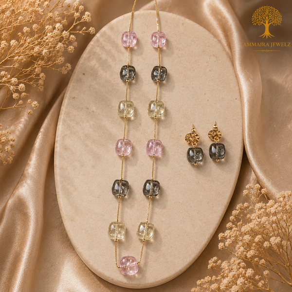 Elegant gold polish mala set with blush pink, smoky grey, and champagne crystal beads paired with matching designer earrings displayed on a model and luxury jewelry stand.