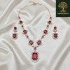 Rose gold necklace set with ruby-red oval and emerald-cut stones, diamond-inspired detailing, and matching earrings, displayed on a satin background, showcasing luxurious bridal jewellery design.