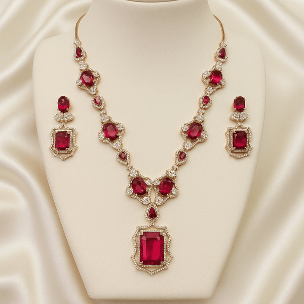 Rose gold necklace set with ruby-red oval and emerald-cut stones, diamond-inspired detailing, and matching earrings, displayed on a satin background, showcasing luxurious bridal jewellery design.
