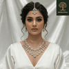 Rose gold bridal necklace set with pear-cut diamond-inspired cascading drops, matching earrings, and coordinating maang tikka, displayed on a black jewellery stand against a satin backdrop.