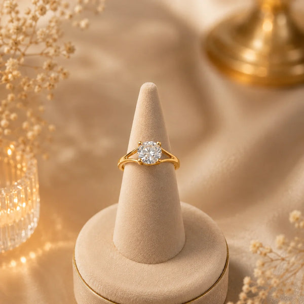 Elegant gold plated solitaire finger ring with a sparkling round crystal displayed in luxury jewelry boxes and worn by a stylish woman.