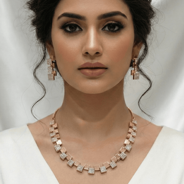 Modern rose gold necklace set with alternating square geometric motifs and matching stud earrings, displayed on a satin background, showcasing minimal luxury jewellery design.