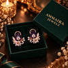 Rose gold floral statement earrings with oval centre stones, leaf motifs and sparkling zirconia detailing, available in ruby red, emerald green, blush pink and deep purple.