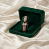Rose gold bracelet in a green velvet box on a beige fabric background