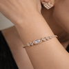 Rose gold bracelet with gemstones on a wrist against a neutral background