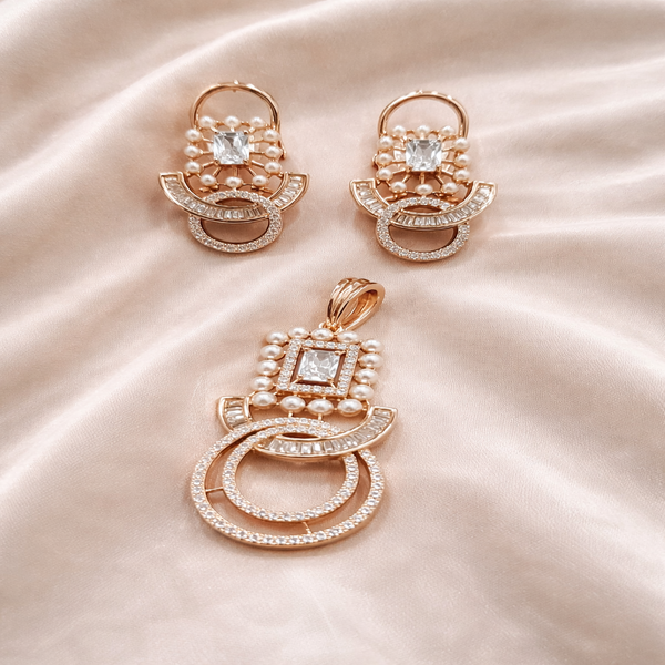 Rose gold jewelry set with earrings and a pendant on a satin surface