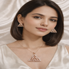 Woman wearing triangle-shaped earrings and a matching necklace against a neutral background