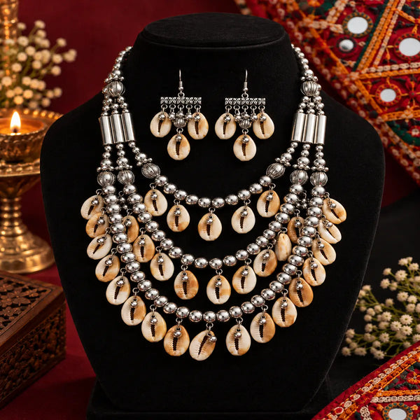 Antique two-tone cowrie shell Navratri necklace set with layered silver-tone beads and matching earrings for women.