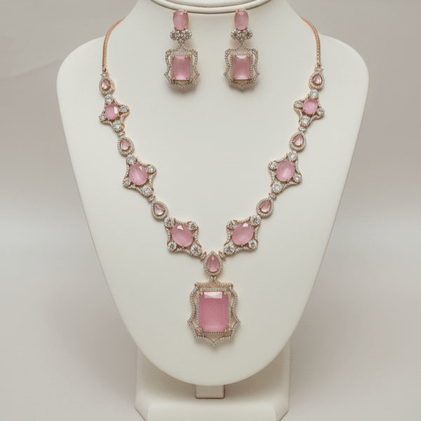 Rose gold necklace set with blush pink oval and rectangular stones, diamond-inspired detailing, and matching drop earrings, displayed on a satin background, showcasing elegant bridal jewellery design.