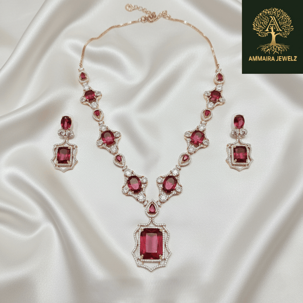 Rose gold necklace set with ruby-red oval and emerald-cut stones, diamond-inspired detailing, and matching earrings, displayed on a satin background, showcasing luxurious bridal jewellery design.