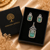 Emerald Élan American Diamond pendant set with emerald green rectangular stones, matching earrings, and sparkling halo detailing in gold polish.