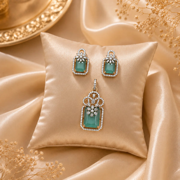 Emerald Élan American Diamond pendant set with emerald green rectangular stones, matching earrings, and sparkling halo detailing in gold polish.