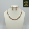 Rose gold necklace set with circular diamond-inspired motifs and matching drop earrings, displayed on a satin fabric background, showcasing elegant and minimal luxury jewellery design.
