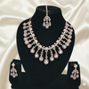 Rose gold bridal necklace set with pear-cut diamond-inspired cascading drops, matching earrings, and coordinating maang tikka, displayed on a black jewellery stand against a satin backdrop.