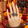 Antique oxidised silver alloy adjustable statement finger ring featuring twin peacock motifs and a beaded floral cluster.