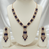Rose gold necklace set with deep blue rectangular stones and an ornate central pendant, paired with matching drop earrings, displayed on a cream jewellery stand against a satin backdrop.