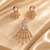 Rose gold American diamond pendant set in premium brass featuring a pear-shaped centre stone, sparkling fan-shaped bars and matching earrings.