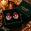 Rose gold floral statement earrings with oval centre stones, leaf motifs and sparkling zirconia detailing, available in ruby red, emerald green, blush pink and deep purple.