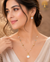 Elegant gold polish pearl mala set with crystal accents, designer beads, statement pearl pendant, and matching pearl earrings displayed on a model and luxury jewelry stand.