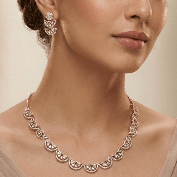 Rose gold scalloped necklace set with diamond-inspired detailing and matching earrings, displayed on a silk cushion against a satin background, showcasing elegant bridal jewellery design.