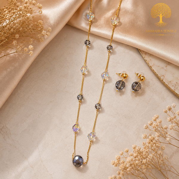 Elegant gold polish mala set with smoky grey and iridescent crystal beads paired with matching crystal earrings displayed on a model and luxury jewelry stand.